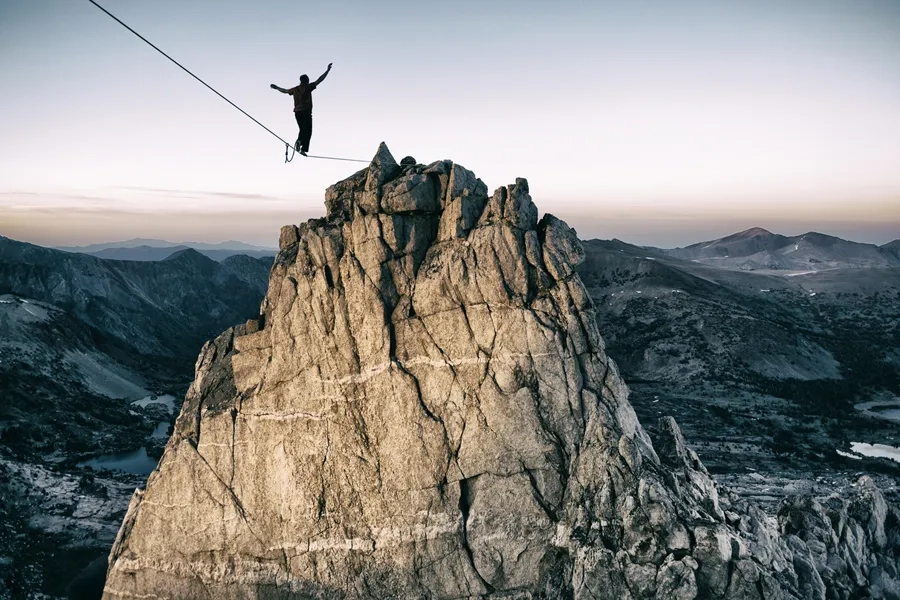Un homme avance sur une corde raide en montagne