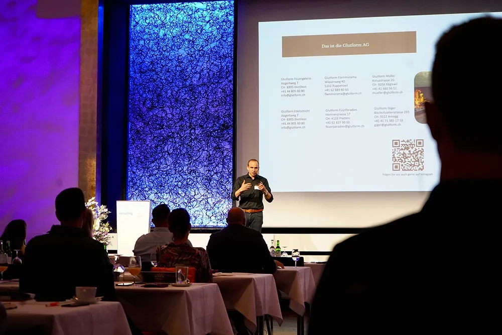 Das Bild zeigt die Bühne der Recruiting Convention in blau-violett, auf der Bühne steht Martin Ritler in Hemd und Jeans.