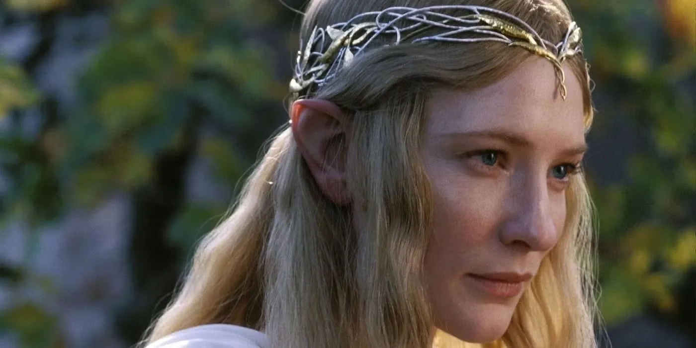 Eine detaillierte Nahaufnahme der Elbenherrin Galadriel, gespielt von Cate Blanchett. Sie ist im Halbprofil zu sehen und blickt mit einem sanften, weisen und fast etwas wehmütigen Ausdruck aus strahlend blauen Augen nach rechts aus dem Bild heraus. Sie hat langes, goldenes, leicht welliges Haar, durch das ihre spitzen Elbenohren deutlich sichtbar sind. Auf dem Kopf trägt sie ein sehr feines, filigranes Diadem, das aus ineinander verschlungenen silbernen Ranken und kleinen goldenen Blättern besteht. An ihrer linken Schulter ist der Ansatz eines fließenden weißen Gewandes zu erkennen. Der unscharfe Hintergrund zeigt weiches, warmes Sonnenlicht, das durch grüne und gelbliche Blätter fällt.