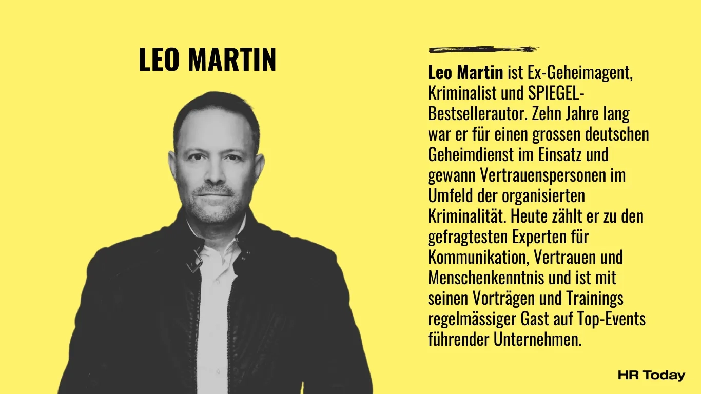 Porträt von Leo Martin, ein Mann mit kurzem dunklem Haar und leichtem Bart, frontal stehend vor hellem Hintergrund, bekleidet mit schwarzer Lederjacke über weissem Hemd und dunkler Hose. Beschreibung: Leo Martin ist Ex-Geheimagent, Kriminalist und SPIEGEL-Bestsellerautor. Zehn Jahre lang war er für einen grossen deutschen Geheimdienst im Einsatz und gewann Vertrauenspersonen im Umfeld der organisierten Kriminalität. Heute zählt er zu den gefragtesten Experten für Kommunikation, Vertrauen und Menschenkenntnis und ist mit seinen Vorträgen und Trainings regelmässiger Gast auf Top-Events führender Unternehmen.